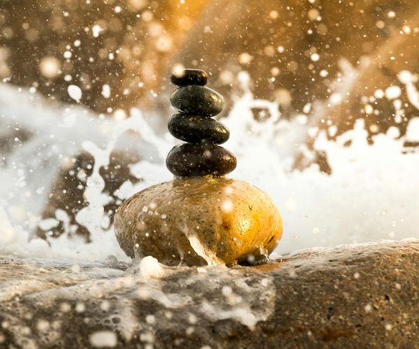 A calm, meditative scene with stacked stones by the water.